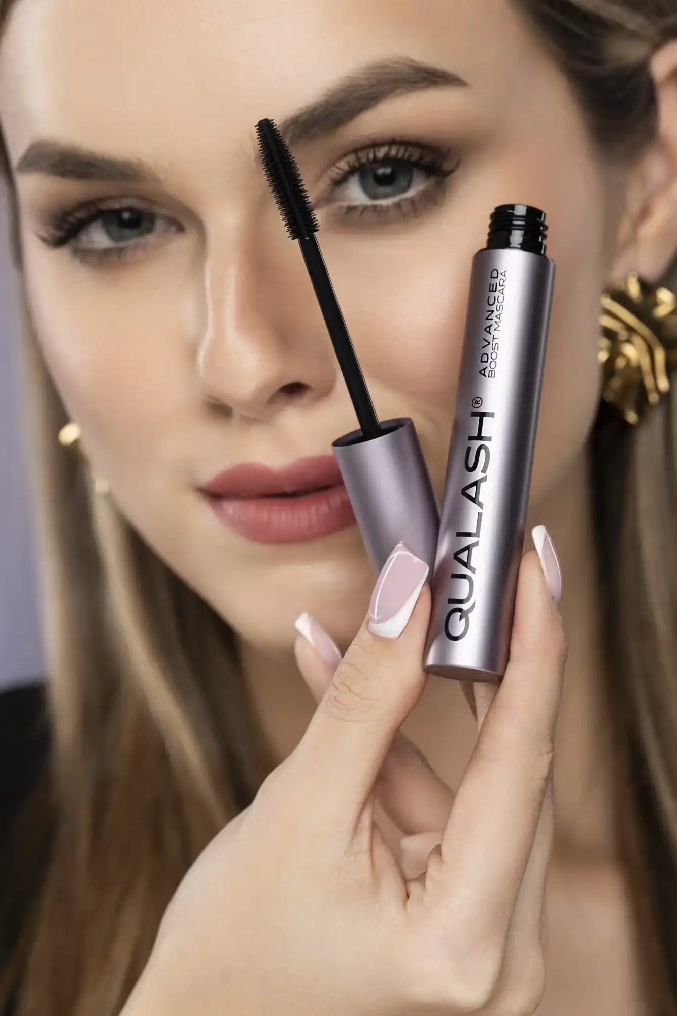 Close-up of woman holding QUALASH Advanced  Volume Max with visible curved brush and voluminous lashes